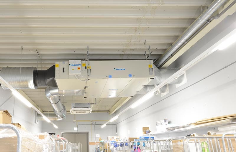 O cameră industrială mare, cu un ventilator de tavan și o lumină de tavan, oferind un spațiu bine iluminat și ventilat.